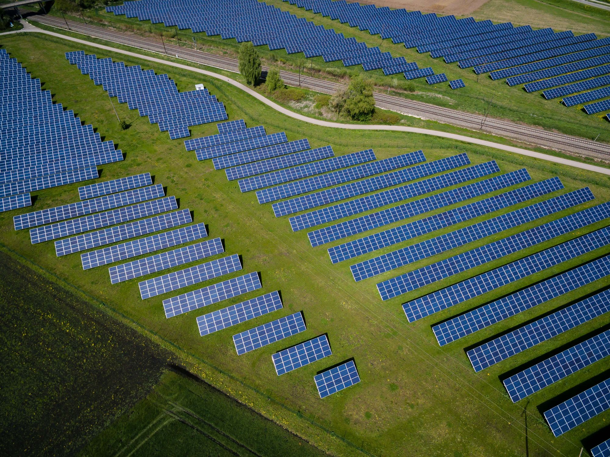 Many rows of solar panels in a green field, seen from the sky high above.