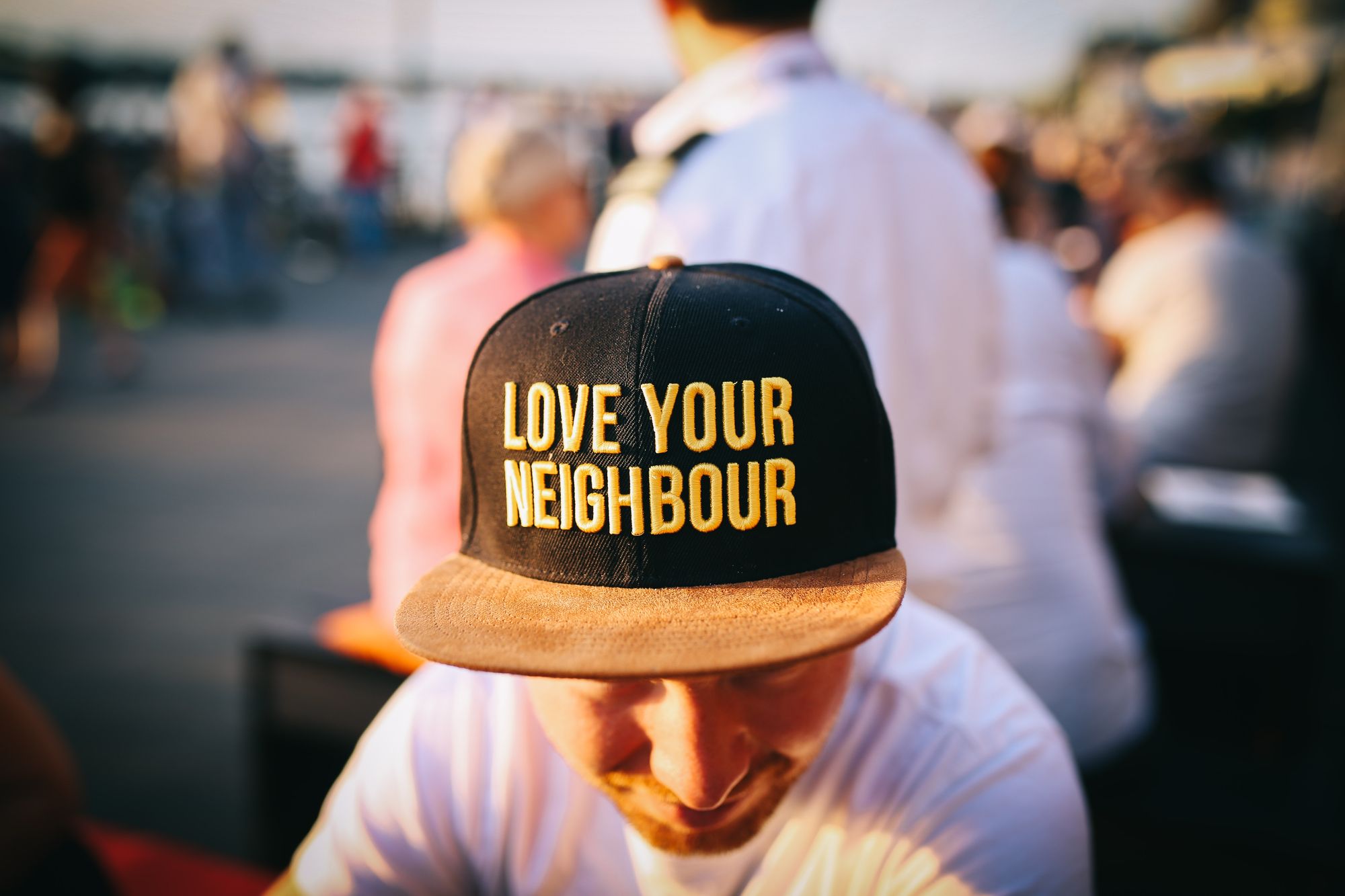 Man in a white t-shirt with a baseball cap that says, "Love Your Neighbour"